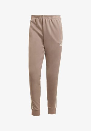 Pantaloni sportivi color marrone chiaro con vestibilità affusolata, cintura elastica e due strisce bianche sui lati; realizzati in un tessuto liscio e leggero.