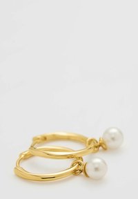 Orecchini a cerchio in oro con una finitura liscia, dotati di un accento di perla bianca su ogni cerchio, che mettono in mostra un design elegante e moderno.