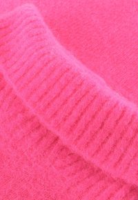 Felle roze trui met een zachte, fuzzy textuur en geribbelde accenten langs de kraag. Hoofdlichaam en kraag zijn uniform van textuur.