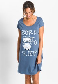 Pigiama di cotone azzurro chiaro con maniche corte e scollo rotondo. Testo "NATO PER DORMIRE" e grafica di un gufo stampata sul davanti.