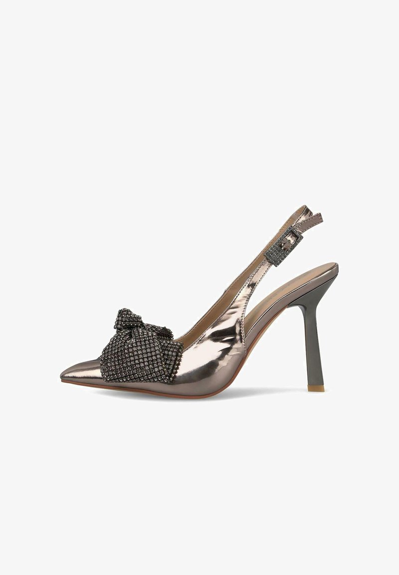Tacón slingback de bronce metálico con puntera puntiaguda, decorado con un lazo negro texturizado y detalles de tachuelas, que presenta un fino tacón de aguja.