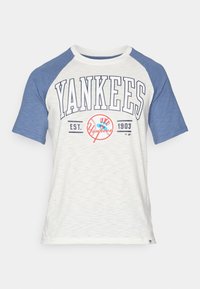 Puuvillasegu T-särk valge keha ja siniste raglanvarrukatega. Omab "YANKEES" teksti ja logo, asutamisaasta "EST. 1903."