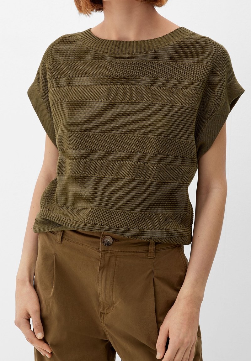 Olive green knitted top with horizontal stripe texture and short sleeves, paired with brown trousers featuring a button closure.