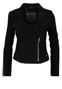 Schwarze Wildlederjacke mit einem geschichteten Kragen, asymmetrischer Vorderseite und silbernen Reißverschlusdetails an den Bündchen und seitlich. Glatte Textur.