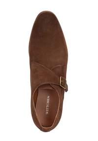 Zapato de ante marrón con punta redondeada, que presenta una tira decorativa con una hebilla de metal. El interior tiene un forro beige y un logotipo de marca grabado.