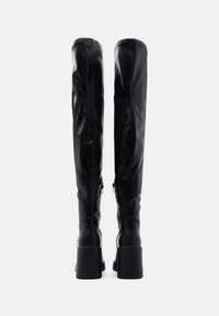 Černé kozačky do výšky kolen vyrobené z hladké kůže, s blokovým podpatkem a zipovým zavíráním. Design je štíhlý s minimálním zdobením.
