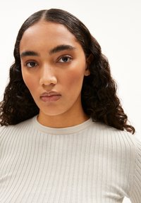 Hellgrau geripptes Oberteil mit Rundhalsausschnitt. Der Stoff hat eine glatte Textur und zeichnet sich durch ein körpernahes Design aus, das den Kragen und die Ärmel betont.