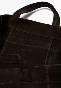 Brun ruskind tote taske med to håndtag, syninger og en præget logoetiket. Blød tekstur med et minimalistisk design.