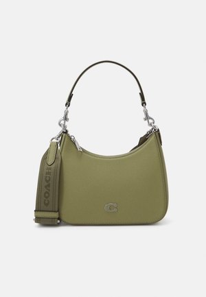 Pequeño bolso de mano verde oliva con asa corta y correa ancha de tela desmontable con el logo de Coach en relieve, cierre de cremallera y detalle del logo en metal.
