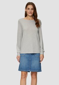 Lichtgrijs lange mouwtop met een boot halslijn, gecombineerd met een blauwe denimrok met twee voorzakken en een rechte snit.