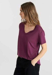 V-hals korte mouwen top in een effen donkere paarse stof, met een losse pasvorm en een gladde textuur, gecombineerd met zwarte broek.