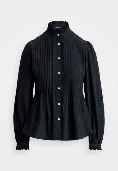 Tmavozelená kockovaná blúzka s vysokým golierom, zapínaním na gombíky a nariasenými pufovými rukávmi. Obsahuje textúrovanú látku a čipkované detaily na manžetách.