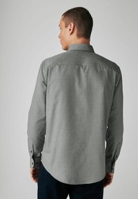 Graues Langarmshirt mit strukturiertem Muster, Knopfmanschetten und abgerundetem Saum. Der Stoff wirkt leicht und lässig.