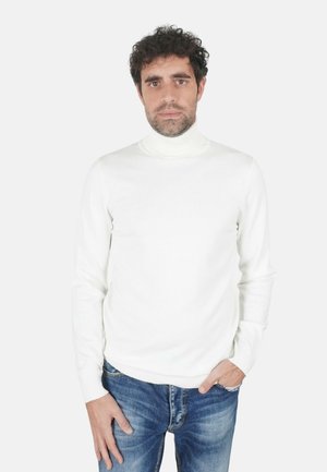 Maglione a collo alto bianco con design aderente, maniche lunghe e polsini a costine, abbinato a jeans blu. Texture liscia, stile semplice.