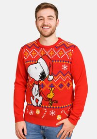 Maglione rosso lavorato a maglia con un design natalizio che presenta Snoopy con un cappello da Babbo Natale, arricchito da motivi e decorazioni colorate come fiocchi di neve.