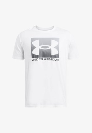 Camiseta de algodón blanca con un logotipo cuadrado gris que presenta un diseño estilizado de "UA" y el texto "UNDER ARMOUR" debajo. Mangas cortas y cuello redondo.