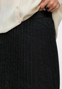 Must mustriga seelik sädelevate detailidega, sujuva musta vöökohtaga, kombineeritud heledat värvi särgiga. Lihtne ja elegantne disain.