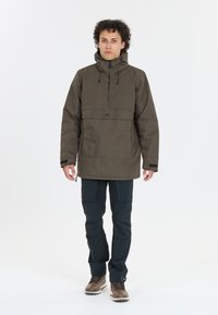 Ruskea neuletakki puolivetoketjulla, säädettävällä hupulla ja etutaskulla; yhdistetty mustiin housuihin ja ruskeisiin saappaisiin. Sujuva ja kestävä kangas.