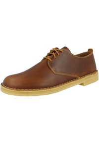 Chaussure en cuir marron à lacets avec une finition lisse, lacets en cuir tan et semelle en crêpe. Présente un orteil arrondi et des détails de surpiqûres contrastées.