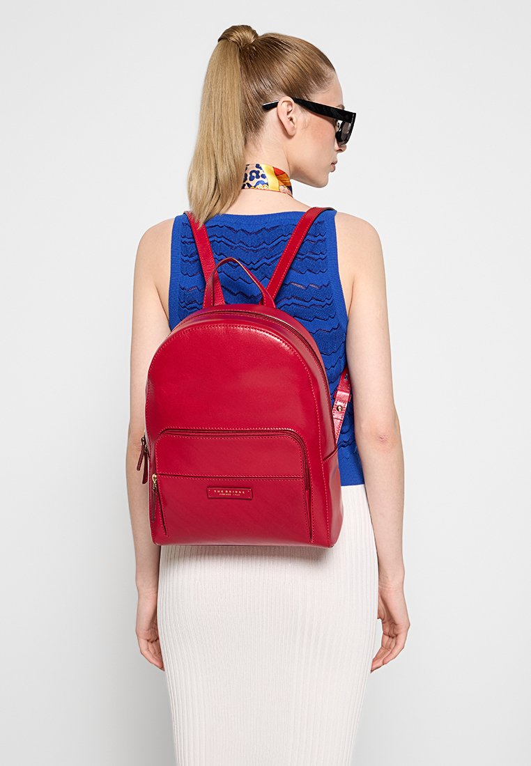 Roter Leder-Rucksack mit gewölbtem Design, verstellbaren Trägern, einer Fronttasche und einer glatten Textur.