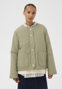 Hellgrüne gesteppte Jacke mit rundem Kragen, Druckknöpfen, zwei vorderen Taschen und einem strukturierten Einsatz in der Mitte.