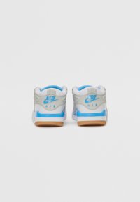 Baskets Nike Air en gris et blanc, avec des accents bleus, un col rembourré et une semelle en caoutchouc. Le design comprend une texture lisse et des détails de logo.