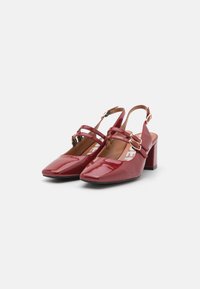 Chaussures à talon slingback en cuir verni rouge avec un bout carré, des fines brides et un talon épais. Présente des accents en métal doré.