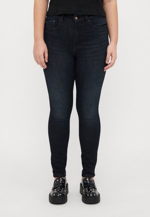 Dark blue skinny jeans in a denim fabric, featuring a front button closure, belt loops, and traditional five-pocket style.