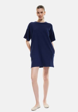 Navy blue oversized t-paita mekko, joka on valmistettu pehmeästä kankaasta, jossa on lyhyet hihat, pyöreä kaula-aukko ja kaksi sivutaskua.