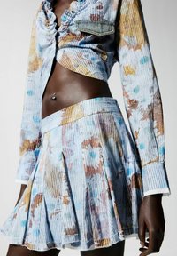 Texturált, pasztell színű, bordázott anyagú ruha szett, amely egy fodros, gombos cropped felsőt és egy virágmintás, pliszírozott szoknyát tartalmaz.