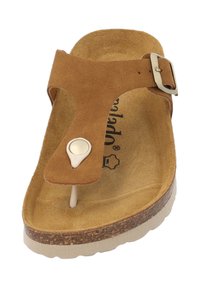 Bruine suède sandaal met een teenpost, verstelbare gesp, zachte voetbed en lichtgekleurde rubberen zool. Heeft een kleine ronde accent.