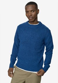 Tengerészkék kötött pulóver kerek nyakkivágással, bordázott mandzsettákkal és alsó szegéllyel. A szöveten texturált minta és finom pici foltok találhatóak.