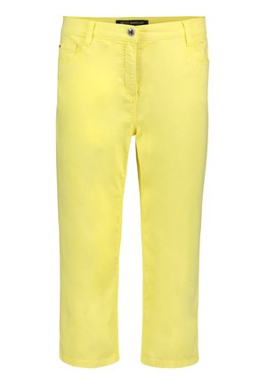 Żółte spodnie o średnim stanie, wąskie, zapinane z przodu na guzik i zamek błyskawiczny, z pętlami na pasek oraz przednimi kieszeniami, o długości za kostkę.