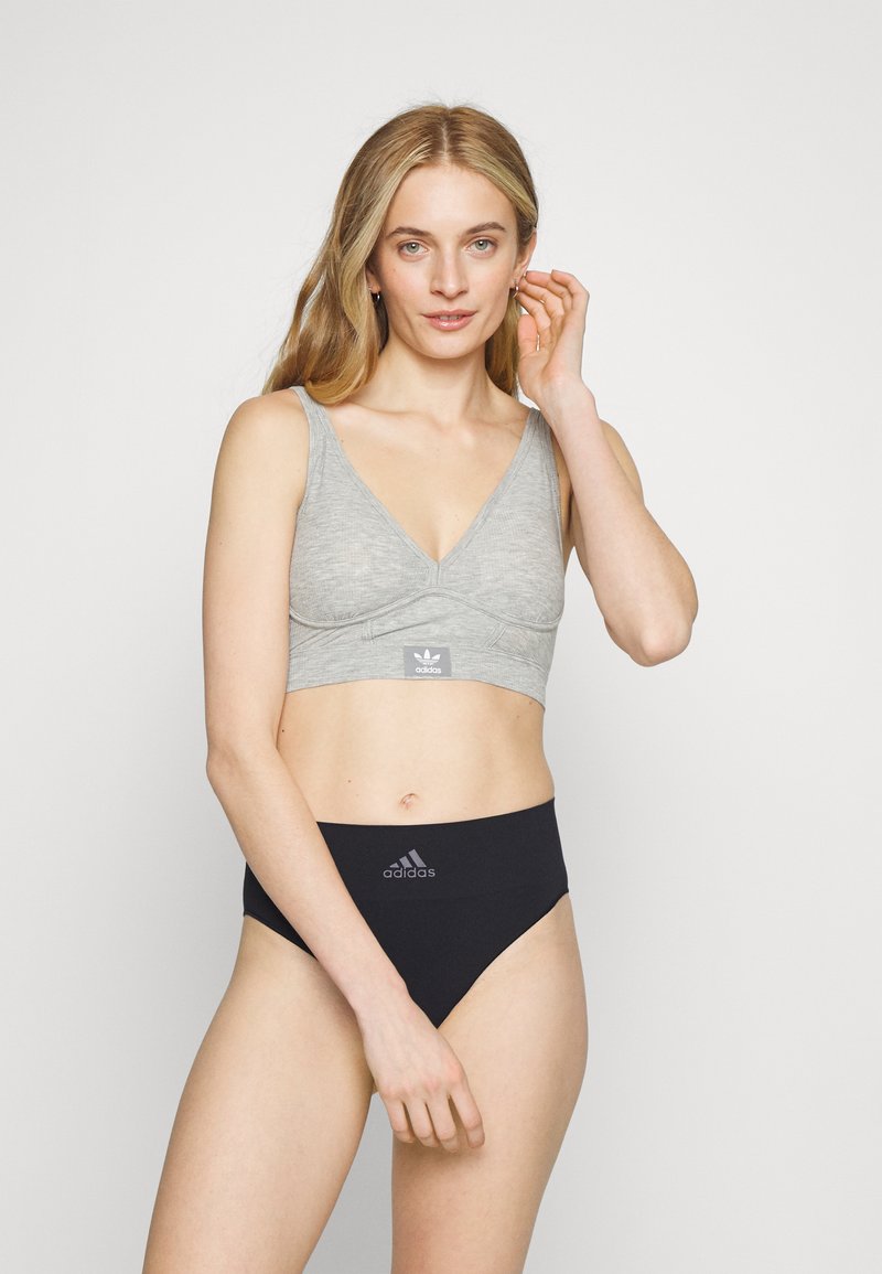 Szürke pamut bralette V nyakkivágással, az Adidas logójával; magas derekú fekete alsóneművel párosítva, szintén az Adidas logójával.