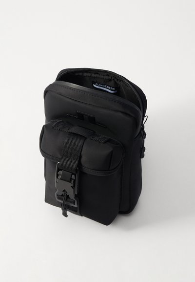 Borsa in nylon nero con un compartimento principale con zip, tasca anteriore con flap sicura tramite una cinghia e dettagli in metallo. Design compatto adatto per gli essenziali.
