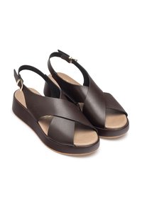 Sandales en cuir marron à talon compensé bas, avec des brides croisées, bout ouvert et accent en boucle dorée.