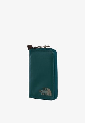 Kompaktowy zielony portfel na zamek z pętlą do chwytania, z logo "THE NORTH FACE" na przednim dolnym rogu.