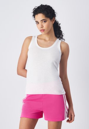 Camiseta sin mangas blanca hecha de un tejido ligero, combinada con pantalones cortos rosa brillante que tienen rayas laterales blancas y una cinturilla elástica.