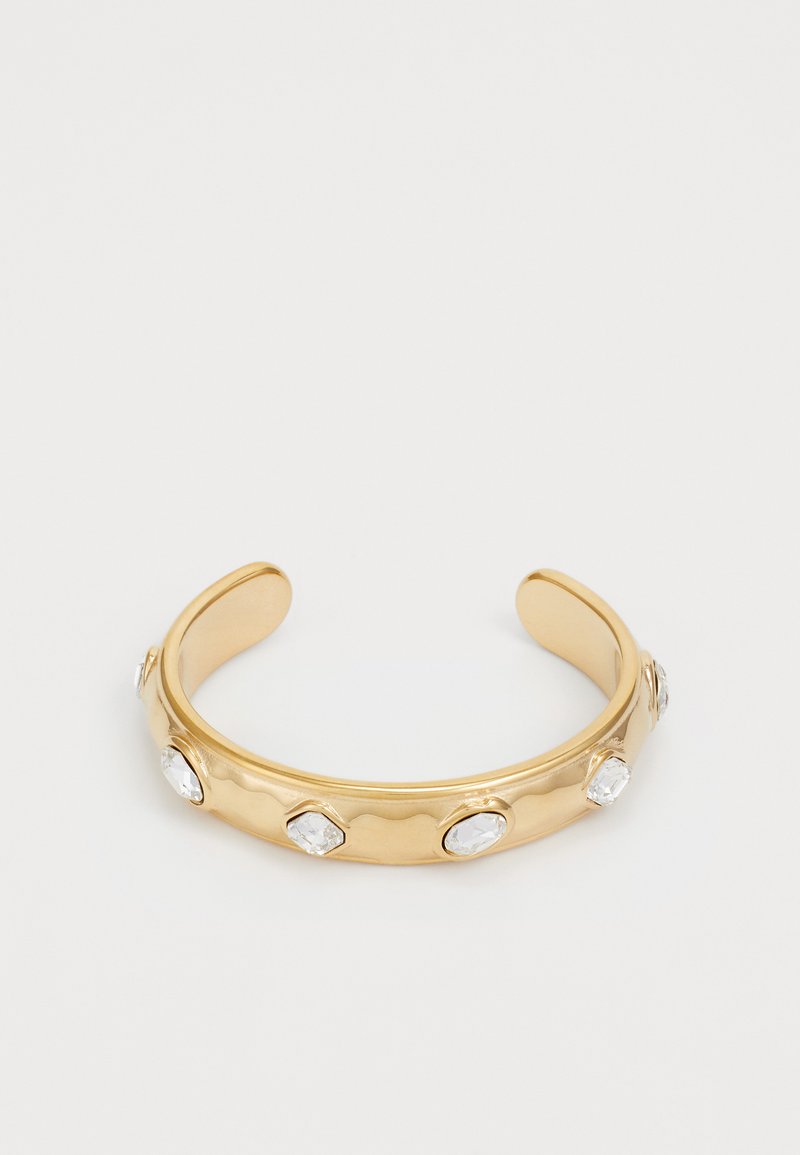 Bracciale rigido in oro con un design ondulato, decorato con sei cristalli ovali trasparenti equidistanti lungo il bracciale. Texture liscia e estremità aperte.