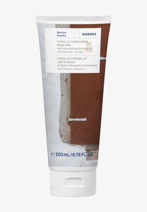 Tube de lait corporel à la vanille et à la cannelle avec huile d'amande nourrissante, 200 mL, marque Korres, bouchon blanc, design abstrait marron et gris sur l'emballage.