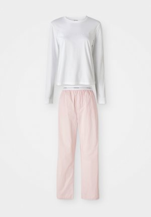 Biała bluzka z długim rękawem z logo "Calvin Klein" oraz jasnoróżowe spodnie, zaprezentowane na czystym tle.