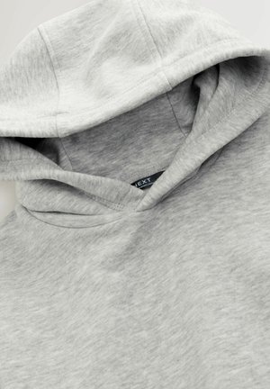 Grauer Kapuzenpullover aus weichem, strukturiertem Stoff, mit großer Kapuze und sichtbarem Markenlabel. Das Design ist einfach, ohne Muster oder Akzente.
