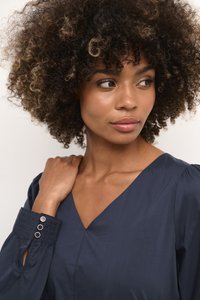 Tumedane kleit V-kaelusega, puffvarrukatega ja tekstureeritud mansettidega, millel on ümmargused lõiked ja metallaktsendid. Sujuv kangas.