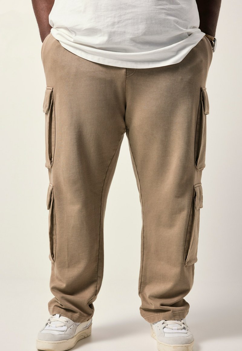 Beige cargobroek van een gestructureerde stof, met twee zijzakken, een taps toelopend ontwerp en een relaxte pasvorm, gecombineerd met witte sneakers.