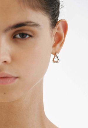 Pendientes en forma de lágrima de plata con un acabado suave y pulido. Diseño ligero, con una curva elegante y sin cierres visibles.