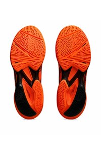 Semelles de chaussures de sport orange avec un motif de semelle complexe, présentant des accents noirs et une surface texturée pour une meilleure adhérence et stabilité.