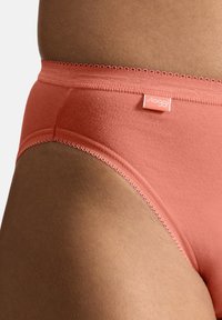 Koraalkleurige dameshipsterondergoed van zacht katoen, met een kantafwerking langs de tailleband en een klein merklabel.