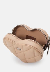 Prošívaná, růžová kožená taška ve tvaru kulaté tašky, se stříbrným kováním a zipovým uzávěrem, který odhaluje uspořádaný interiér se slotem na karty.