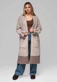 Cardigan lungo lavorato a maglia in grigio chiaro con strisce marroni e crema, con dettagli rosa e blu sui polsini e due tasche frontali.