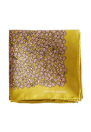 Tissu jaune plié avec un motif dense de petites fleurs roses et de feuilles vertes, texte «&OTHER STORIES» imprimé en blanc dans un coin.